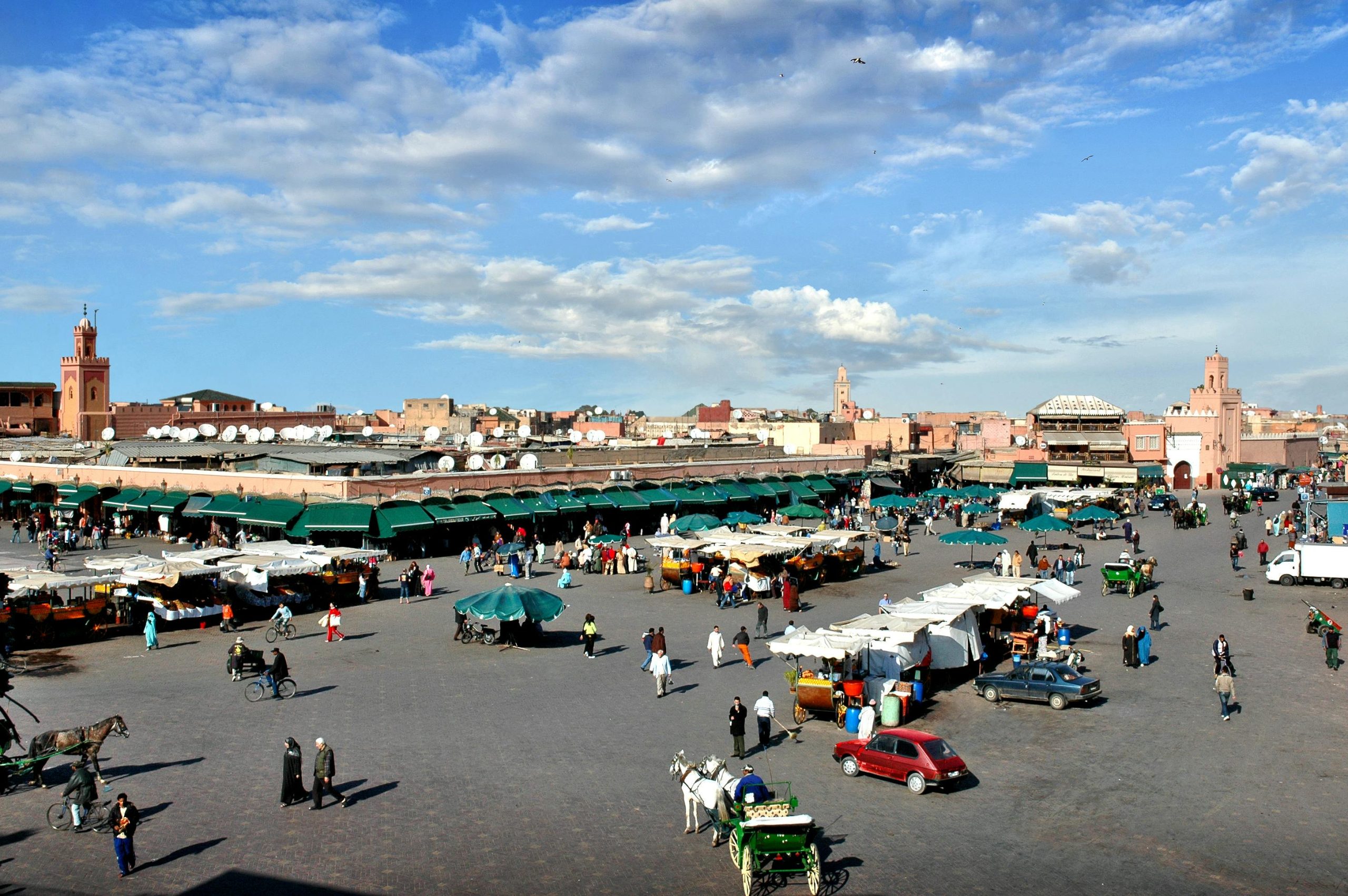 Crowds of people walking through Jemaa el-Fnaa square in Marrakech, Morocco surrounded by market stalls and traditional architecture